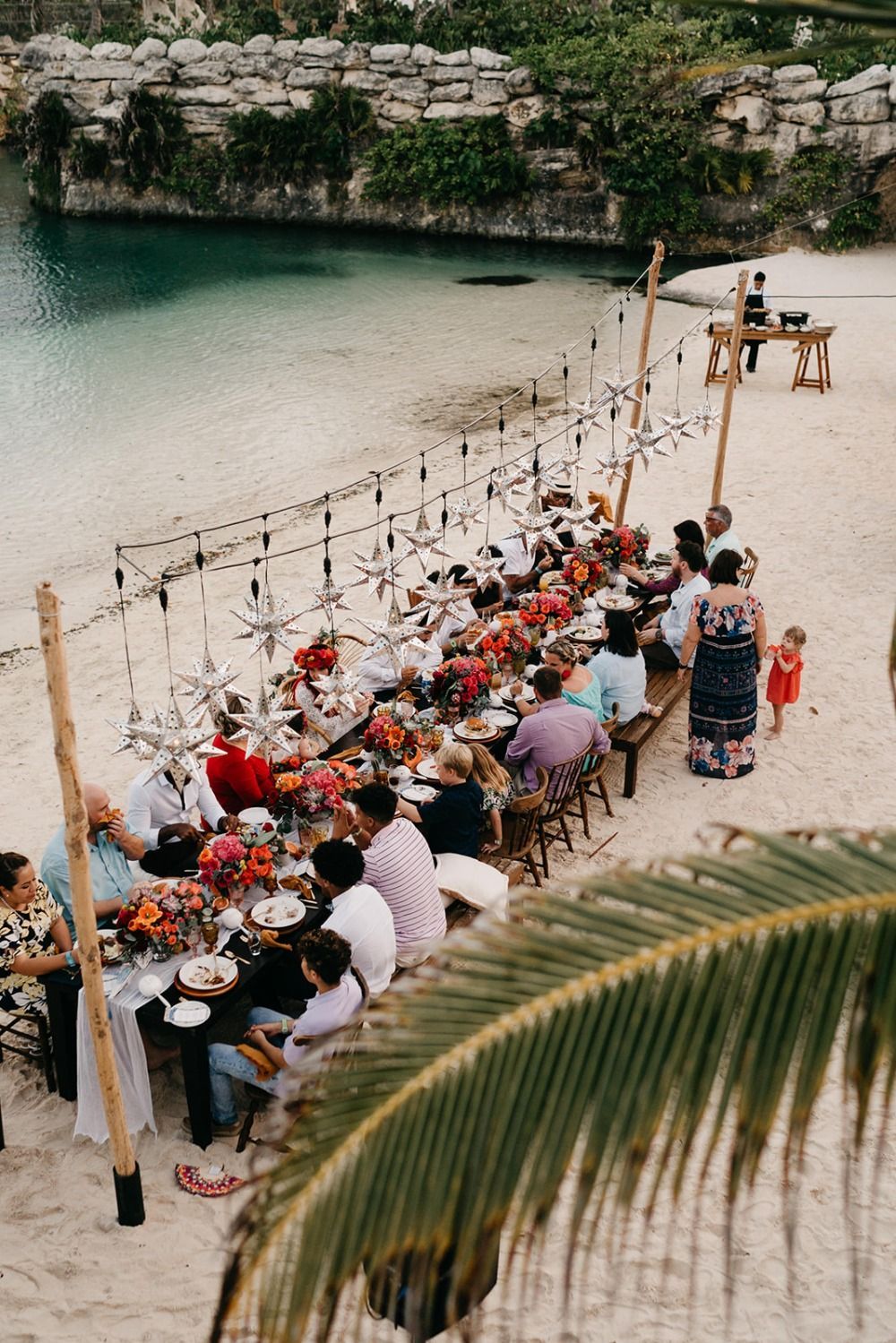 Guests seated at a beach reception table near Xcaret water and stone.